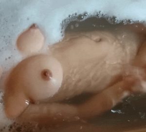 Pregnant woman with pierced nipple taking a bath